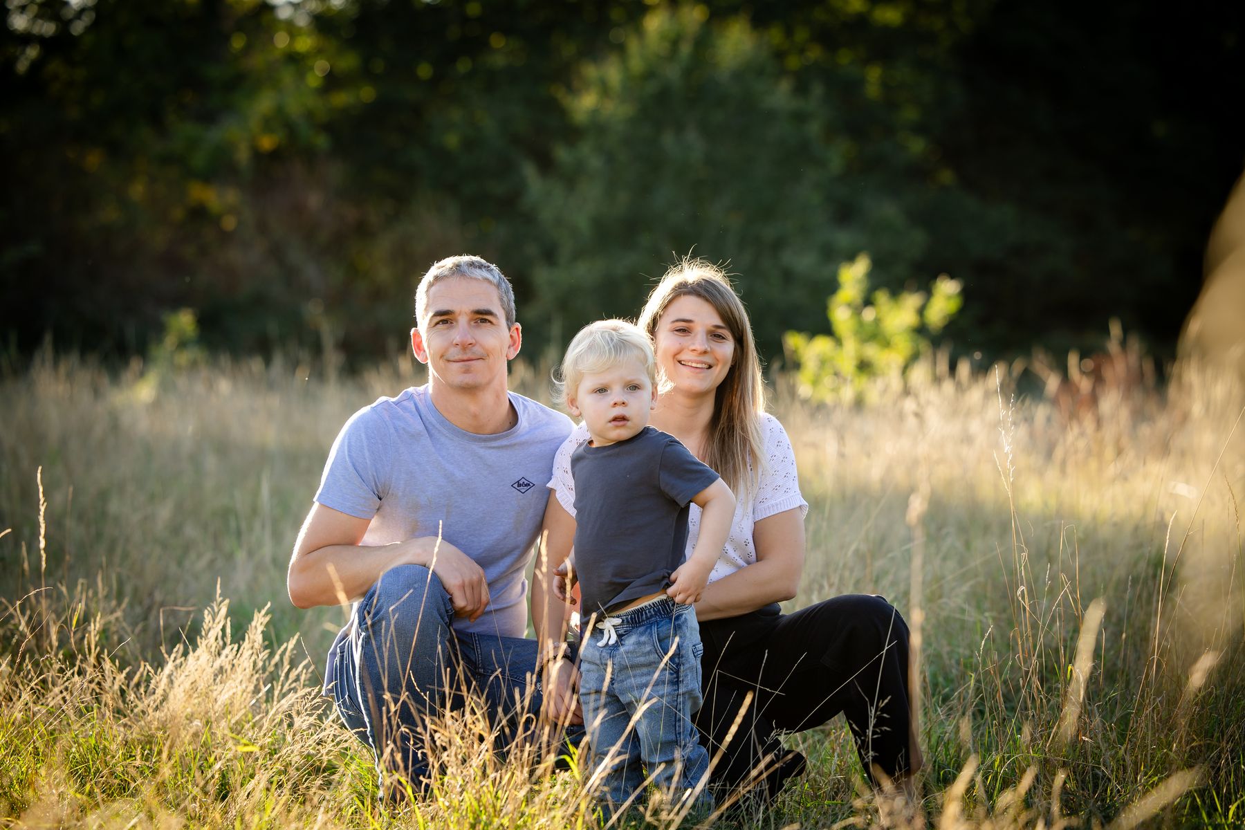Parents and toddler in a golden meadow at sunset
